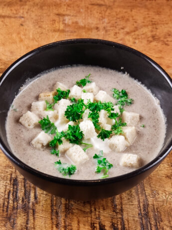 Creamy champignon soup with sour cream, parsley and croutons