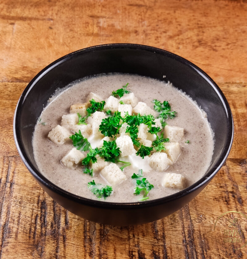 Creamy champignon soup with sour cream, parsley and croutons