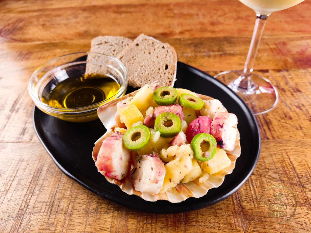 Potato octopus salad served with homemade bread, olive oil and a glass of white wine